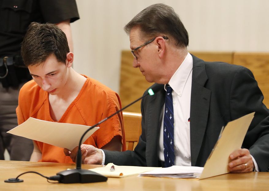 Alexander M. Kraus, 17, is handed documents by his attorney Gregory Petit during his initial appearance Tuesday, April 16, 2019, in the Outagamie County Circuit Court in Appleton, Wis. Kraus was charged with two counts of first-degree intentional homicide for the deaths of his grandparents, 74-year-old Dennis Kraus and 73-year-old Letha Kraus. Each charge carries a life sentence. (Danny Damiani/The Post-Crescent via AP)