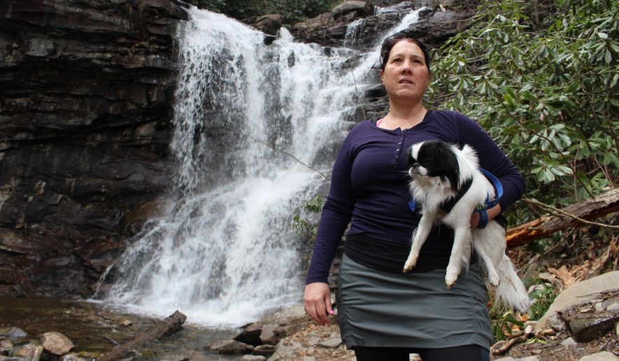 Jacqueline Zito poses for a portrait with her dog, Sally, at the base of Glen Onoko Falls in Jim Thorpe, Pa., Tuesday, April 16, 2019. Zito and other hikers are opposed to a Pennsylvania Game Commission plan to shut down the popular falls trail over safety concerns. Pennsylvania officials are closing one of the most scenic and popular hiking trails in the state because of longstanding concerns about its safety, prompting backlash from hikers. (AP Photo/Michael Rubinkam)