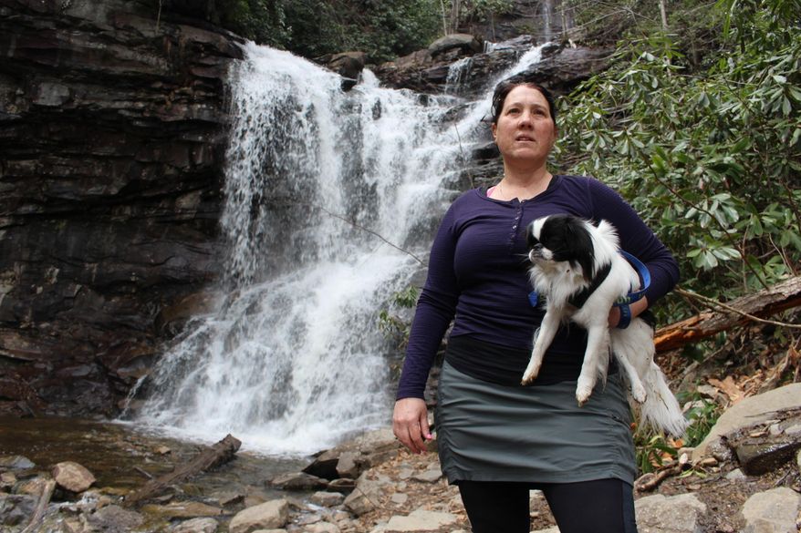 Jacqueline Zito poses for a portrait with her dog, Sally, at the base of Glen Onoko Falls in Jim Thorpe, Pa., Tuesday, April 16, 2019. Zito and other hikers are opposed to a Pennsylvania Game Commission plan to shut down the popular falls trail over safety concerns. Pennsylvania officials are closing one of the most scenic and popular hiking trails in the state because of longstanding concerns about its safety, prompting backlash from hikers. (AP Photo/Michael Rubinkam)