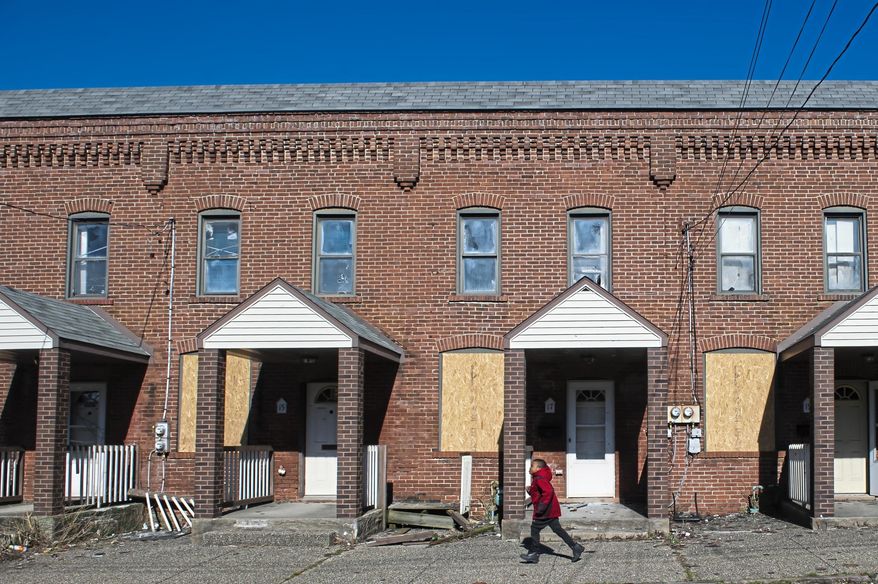 A child runs past a line of boarded up row homes on Tuesday, March 26, 2019, in Duquesne. Duquesne, home to slightly more than 5,500 residents, is one of seven Allegheny County municipalities in which half of or more of the kids live in poverty. (Stephanie Strasburg/Post-Gazette via AP)