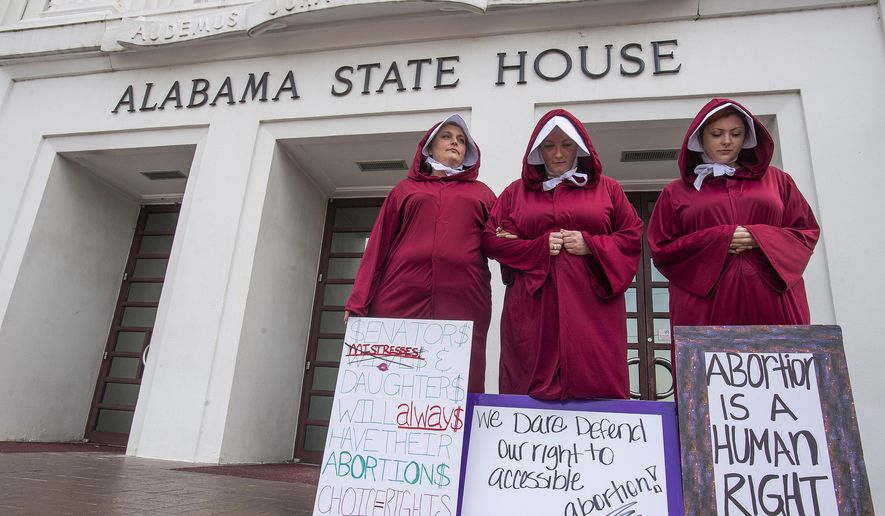 Bianca Cameron-Schwiesow, from left,Kari Crowe and Margeaux Hardline, dressed as handmaids, take part in a protest against HB314, the abortion ban bill, at the Alabama State House in Montgomery, Ala., on Wednesday April 17, 2019. (Mickey Welsh/The Montgomery Advertiser via AP)