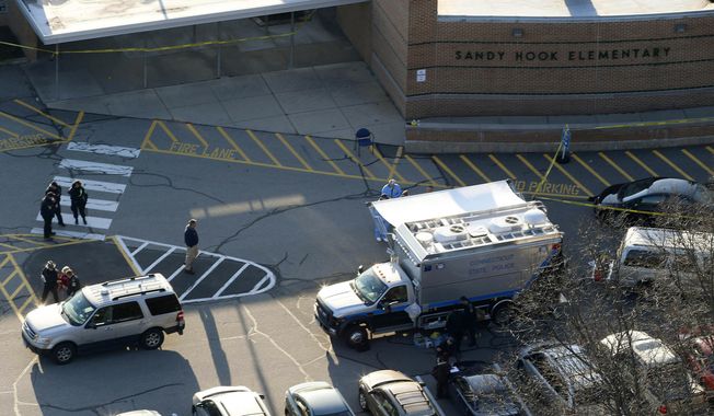 In this Dec. 14, 2012, aerial file photo, officials stand outside of Sandy Hook Elementary School in Newtown, Conn., where gunman Adam Lanza opened fire inside school killing 20 first-graders and six educators at the school. A Connecticut appeals court is scheduled to hear arguments on Wednesday, April 17, 2019, on whether parents of some of the shooting victims can sue the town for school officials&#x27; alleged failure to follow security protocols once the shooting began. (AP Photo/Julio Cortez, File)