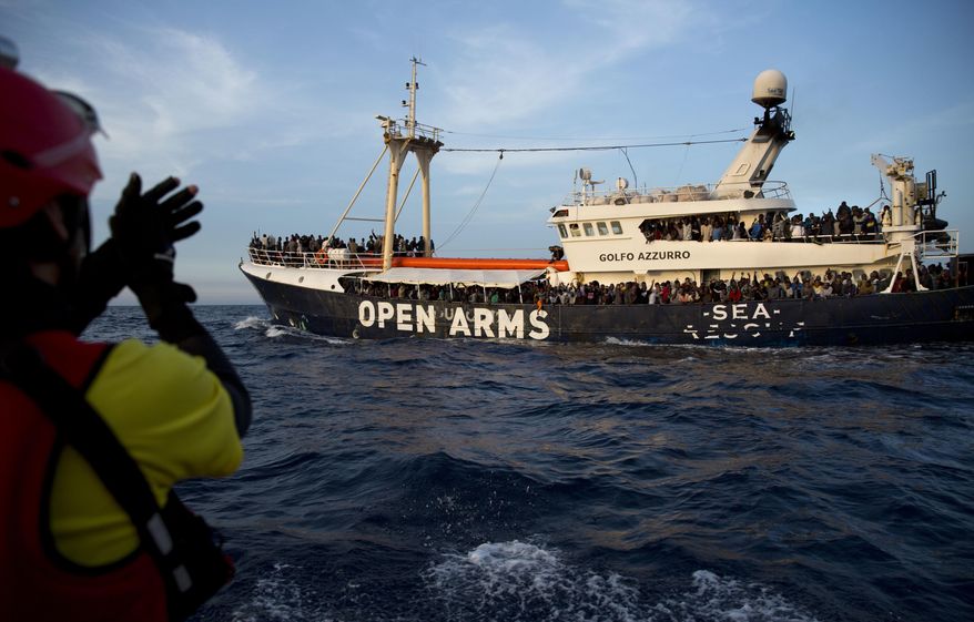 FILE - In this Thursday, June. 15, 2017 file photo, migrants and refugees react at the rescue vessel Golfo Azzurro after being rescued by Spanish NGO Proactiva Open Arms workers in the Mediterranean Sea, about 18 miles north of Sabratha, Libya. Spanish aid groups say Spain is allowing them to deliver aid supplies to refugee camps in Greek islands, but they face hefty fines if their boats venture into official search and rescue areas in the Central Mediterranean. (AP Photo/Emilio Morenatti, File)