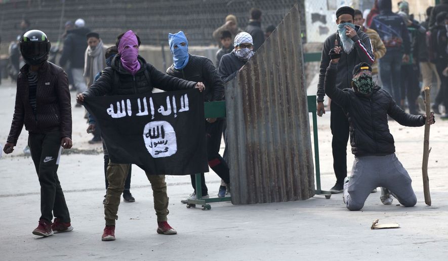 A Kashmiri protester shows Islamic state flag as others clash with Indian policemen during a protest in Srinagar, Indian controlled Kashmir, Friday, Dec. 7, 2018. Government forces fired pellet guns on Kashmiris who gathered after Friday afternoon prayers protesting against Indian rule in the disputed region. (AP Photo/ Dar Yasin)