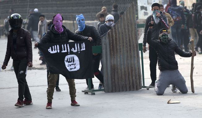 A Kashmiri protester shows Islamic state flag as others clash with Indian policemen during a protest in Srinagar, Indian controlled Kashmir, Friday, Dec. 7, 2018. Government forces fired pellet guns on Kashmiris who gathered after Friday afternoon prayers protesting against Indian rule in the disputed region. (AP Photo/ Dar Yasin)