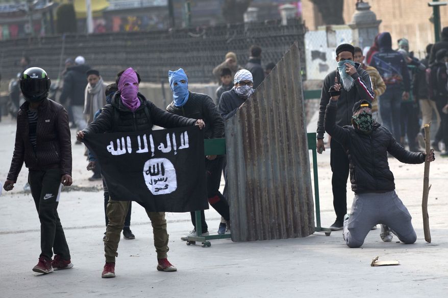 A Kashmiri protester shows Islamic state flag as others clash with Indian policemen during a protest in Srinagar, Indian controlled Kashmir, Friday, Dec. 7, 2018. Government forces fired pellet guns on Kashmiris who gathered after Friday afternoon prayers protesting against Indian rule in the disputed region. (AP Photo/ Dar Yasin)
