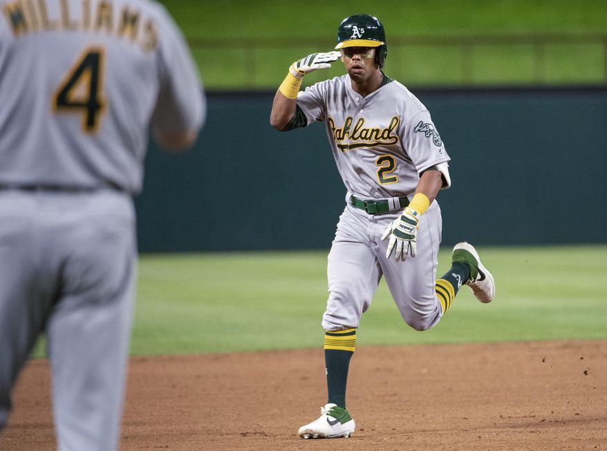 Oakland Athletics' Khris Davis (2) salutes third base coach Matt Williams (4) as he nears third on a solo home run off Texas Rangers relief pitcher Chris Martin during the eighth inning of a baseball game Friday, April 12, 2019, in Arlington, Texas. Oakland won 8-6. (AP Photo/Jeffrey McWhorter)