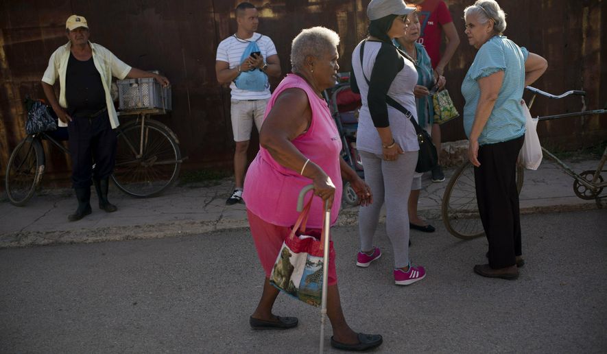 Pura Castell walks to a government-run butcher shop to buy chicken, after failing to find chicken the previous day in Bauta, Cuba, Friday, April 12, 2019. A neighbor informed her that chicken had arrived at the government store that distributes almost free monthly food rations. (AP Photo/Ramon Espinosa)