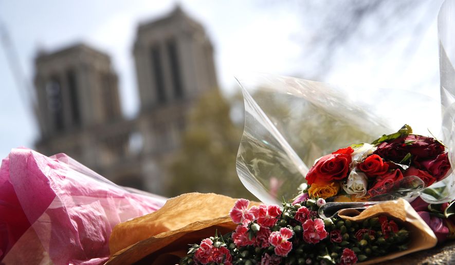 Flowers and tributes are left outside the Notre Dame Cathedral in Paris, Thursday, April 18, 2019. Nearly $1 billion has already poured in from ordinary worshippers and high-powered magnates around the world to restore Notre Dame Cathedral in Paris after a massive fire. (AP Photo/Christophe Ena)