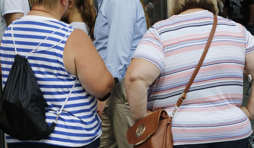 FILE - In this Tuesday, Aug. 16, 2016 file photo, two overweight women tour the World Trade Center in New York. A study published by the journal Cell on Thursday, April 18, 2019 suggests that a genetic test can identify newborns at heightened risk of becoming severely obese by middle age, possibly giving time for interventions designed to head off that fate. (AP Photo/Mark Lennihan)