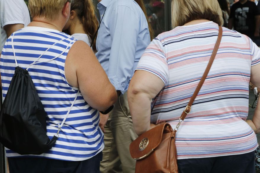 FILE - In this Tuesday, Aug. 16, 2016 file photo, two overweight women tour the World Trade Center in New York. A study published by the journal Cell on Thursday, April 18, 2019 suggests that a genetic test can identify newborns at heightened risk of becoming severely obese by middle age, possibly giving time for interventions designed to head off that fate. (AP Photo/Mark Lennihan)