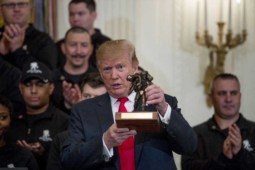 President Donald Trump holds up a statue of the Wounded Warrior Project logo presented to him during a Wounded Warrior Project Soldier Ride event in the East Room of the White House, Thursday, April 18, 2019, in Washington. (AP Photo/Andrew Harnik)