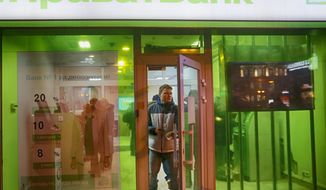 FILE - In this file photo taken on Monday, Dec. 19, 2016, a client leaves PrivatBank as other clients take money from PrivatBank&#39;s cash machine in Kiev, Ukraine. A Ukrainian court has ruled that the 2016 nationalization of the major bank PrivatBank, owned by a powerful tycoon Ihor Kolomoyskyi, was illegal. (AP Photo/Efrem Lukatsky, File)