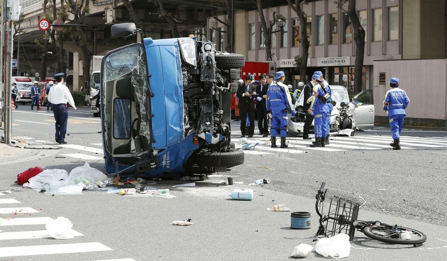 Police officers inspect the scene of a car accident in Tokyo Friday, April 19, 2019. A car, right rear, driven by an 87-year-old man crashed into a garbage truck, foreground, on a Tokyo street Friday, killing a woman and a girl who were on a bicycle, according to police. (Shinji Kita/Kyodo News via AP)