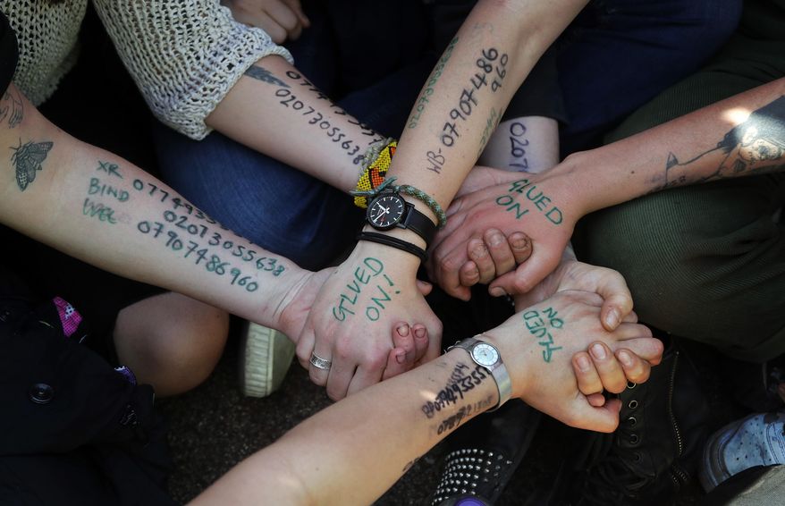 Protestors hold their hands glued together at Oxford Circus in London, Friday, April 19, 2019. The group Extinction Rebellion is calling for a week of civil disobedience against what it says is the failure to tackle the causes of climate change. (AP Photo/Frank Augstein)