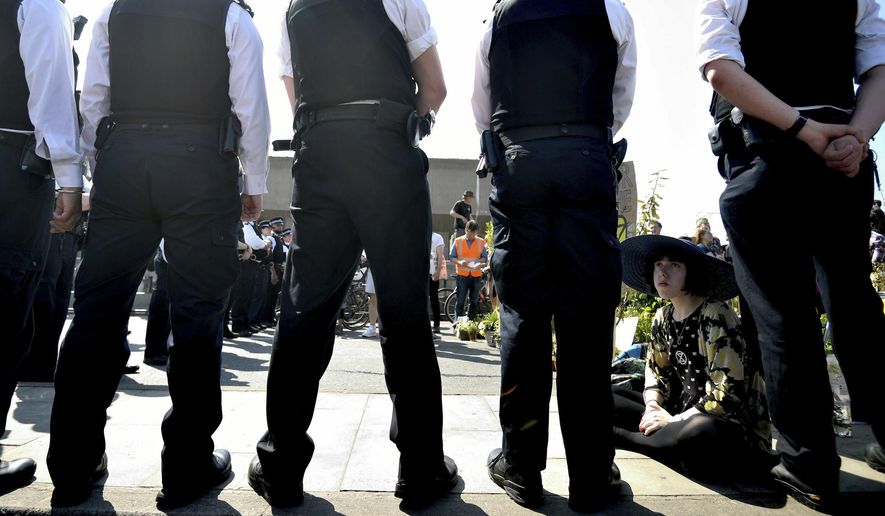 Police speak to a demonstrator on the main thoroughfare on Waterloo Bridge in central London, Saturday April 20, 2019. Climate protesters with the environmental pressure group Extinction Rebellion are once again shutting down parts of London using civic disobedience to urge residents and government to do more to protect the Earth from rising temperatures.(Victoria Jones/PA via AP)
