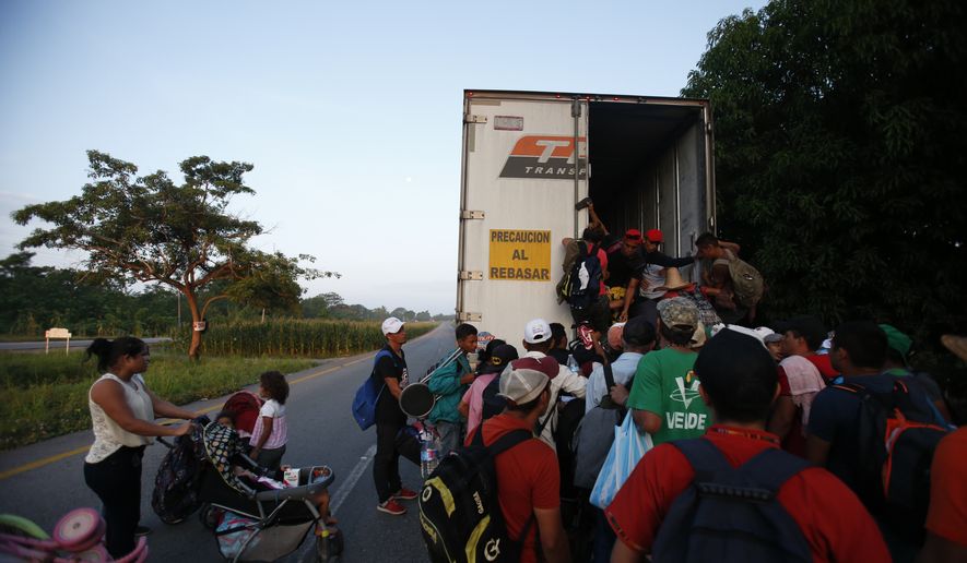 Central American migrants climb into the back of a tractor trailer as a thousands strong caravan makes its way north hoping to reach the U.S. border, between Pijijiapan and Tonala, Mexico, Friday, Oct. 26, 2018. Many migrants said they felt safer traveling and sleeping with several thousand strangers in unknown towns than hiring a smuggler or trying to make the trip alone.(AP Photo/Rebecca Blackwell)