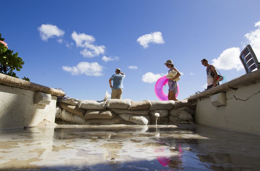 In this June 21, 2017 photo, a puddle of seawater forms behind sandbags at a hotel on Waikiki Beach in Honolulu as record high tides begin to hit the state. Some of Hawaii's most iconic beaches could soon be underwater as rising sea levels caused by global warming overtake its white sand beaches and bustling city streets. That’s alarming for a state where beach tourism is the primary economic driver. (Honolulu Star-Advertiser, Cindy Ellen Russell via AP)
