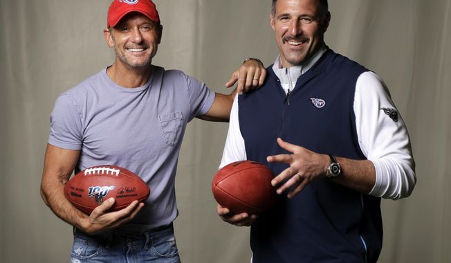 CORRECTS TO THE SECOND DAY OF THE NFL DRAFT, ON APRIL 26 - In this April 18, 2019, photo, country music star Tim McGraw, left, poses with Tennessee Titans head coach Mike Vrabel in Nashville, Tenn. After the second day of the of the NFL Draft in Nashville on Friday, April 26, McGraw will cap off the evening performing on the draft stage across the Cumberland River from Nissan Stadium, home of the Tennessee Titans. (AP Photo/Mark Humphrey)