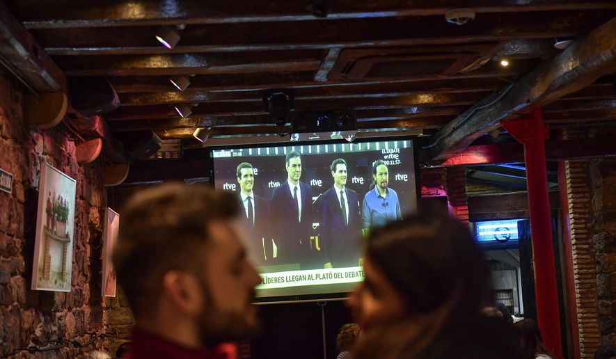 People watch a live televised general election debate between four main candidates, left to right, Pablo Casado of Popular Party, Spain acting Primer Minister Pedro Sanchez of Socialist Party, Albert Rivera of Citizen's Party and Pablo Iglesias of Podemos Party, in Pamplona, Spain, Monday April 22, 2019. The debate is the first of two televised debates after Spain's electoral board barred the far-right Vox party from participating because it has no presence in the country's parliament. Spain goes to the polls next April 28. (AP Photo/Alvaro Barrientos)