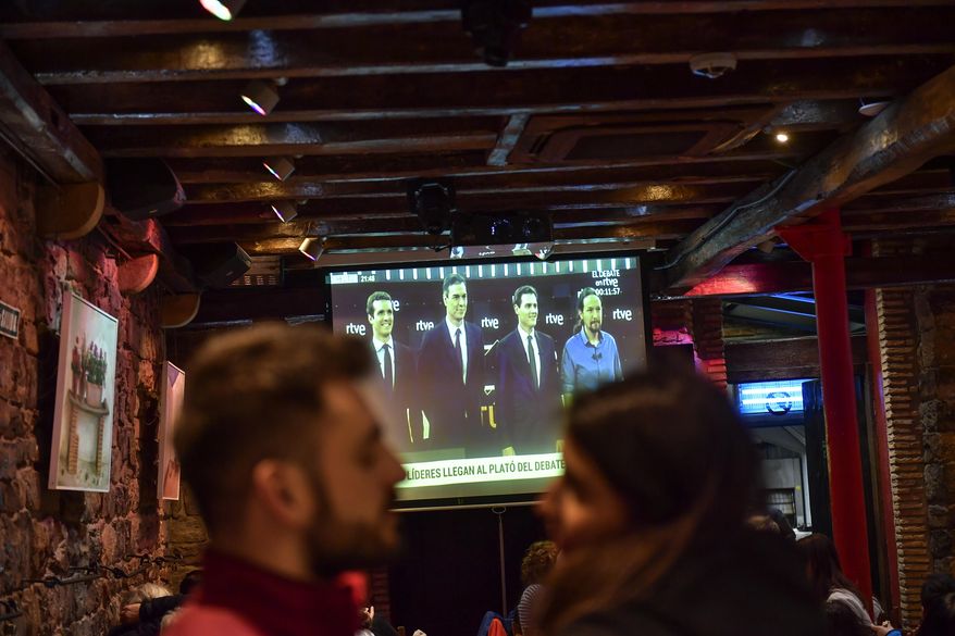 People watch a live televised general election debate between four main candidates, left to right, Pablo Casado of Popular Party, Spain acting Primer Minister Pedro Sanchez of Socialist Party, Albert Rivera of Citizen's Party and Pablo Iglesias of Podemos Party, in Pamplona, Spain, Monday April 22, 2019. The debate is the first of two televised debates after Spain's electoral board barred the far-right Vox party from participating because it has no presence in the country's parliament. Spain goes to the polls next April 28. (AP Photo/Alvaro Barrientos)