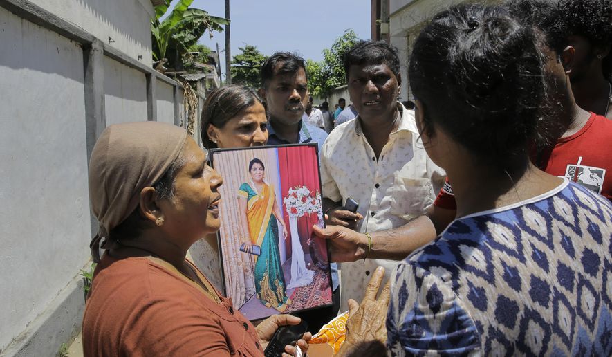 A Sri Lankan woman enquires about her relative holding her photographs outside hospital morgue, a day after the serial blasts in Colombo, Sri Lanka, Monday, April 22, 2019. A government crime investigator says the coordinated Easter bombings that ripped through Sri Lankan churches and luxury hotels were carried out by seven suicide bombers which killed and injured hundreds of people, was Sri Lanka's deadliest violence since a devastating civil war in the South Asian island nation ended a decade ago. (AP Photo/Eranga Jayawardena)
