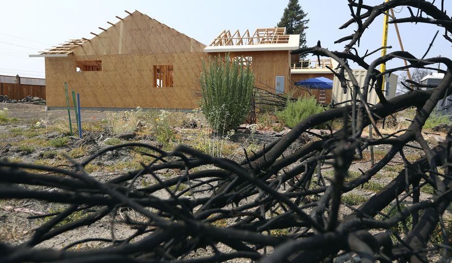 FILE - This Aug. 9, 2018 file photo shows a burned tree in the foreground of Cheri Sharp's new home under construction in Santa Rosa, Calif. Years of increasingly deadly wildfires that ripped through California communities are spurring measures that would toughen local governments' requirements for approving housing developments in high risk areas. Developers would have to increase fire protections, plan for evacuations, or prepare for residents who may need to ride out fires in safe areas. The building industry says the regulations could worsen California's persistent problems with homelessness and affordable housing. (AP Photo/Lorin Eleni Gill, File)