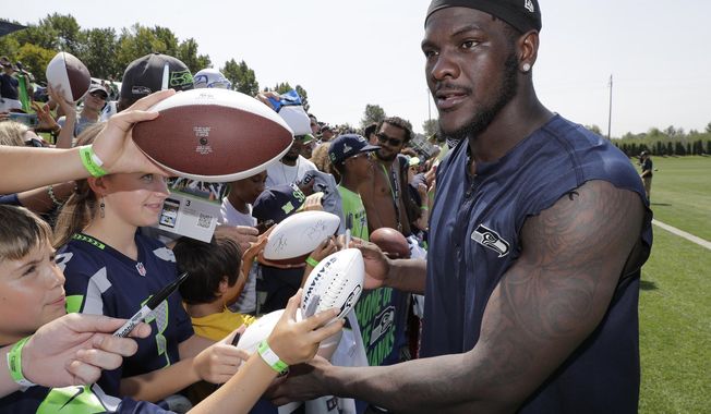 FILE - In this Aug. 6, 2018, file photo, Seattle Seahawks defensive end Frank Clark signs autographs following NFL football training camp, in Renton, Wash. The Kansas City Chiefs have agreed to acquire defensive end Frank Clark from the Seattle Seahawks in exchange for a first-round draft pick this year and a second-round pick in 2020. Almost immediately after word leaked of the trade on Tuesday, April 23, 2019, Clark and the Chiefs worked quickly to reach agreement on a five-year contract worth up to $105 million, according to a person with knowledge of the deal. The person spoke to The Associated Press on the condition of anonymity because the deal had not been announced by either team and was still pending a physical.(AP Photo/Ted S. Warren, File)