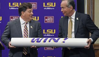 LSU president F. King Alexander, right, and Scott Woodward, left, hoist the &#39;WIN!&#39; bar after Woodward was introduced as the new Director of Athletics for LSU, Tuesday April 23, 2019, in Baton Rouge, La. Woodward, who graduated from LSU in 1985, was the Vice-Chancellor of External Affairs at his alma mater under former Chancellor Mark Emmert from 2000-2004. Woodward spent time at Washington and Texas A&amp;amp;M before accepting the job at LSU as a replacement for Joe Alleva. (Bill Feig/The Advocate via AP)