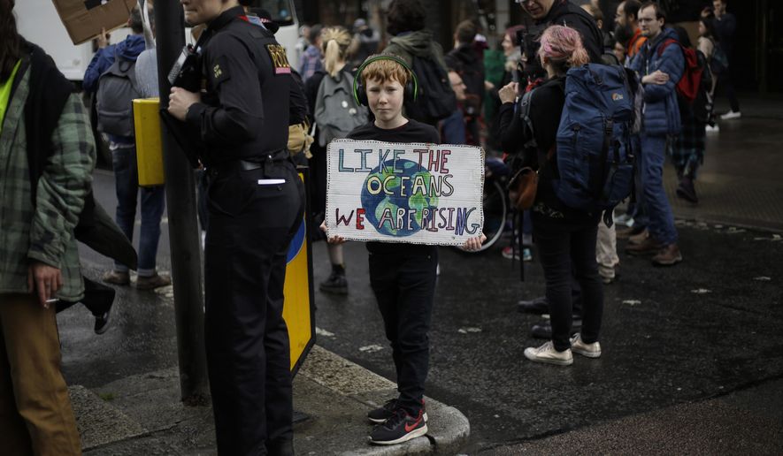 A young Extinction Rebellion climate change protester holds a banner as they briefly block a road in central London, Wednesday, April 24, 2019. The non-violent protest group, Extinction Rebellion, is seeking negotiations with the government on its demand to make slowing climate change a top priority. (AP Photo/Matt Dunham)