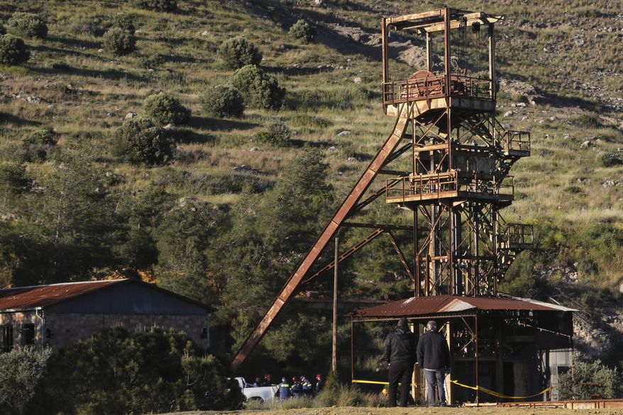 Men stand and watch the investigators by a flooded mineshaft where two female bodies were found, outside of Mister village near capital Nicosia, Cyprus, Monday, April 22, 2019. Police on the east Mediterranean island nation, along with the help of the fire service, are conducting the search Monday in the wake of last week's discovery of the bodies in the abandoned mineshaft and the disappearance of the six year-old daughter of one of the victims. (AP Photo/Petros Karadjias)