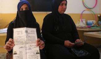 In this Feb. 26, 2019 photo, Nour Ahmed, who says says her husband was snatched by unknown assailants two years ago, displays her marriage document, issued by the Islamic State group, at a legal clinic supported by the Norwegian Refugee Council, in west Mosul, Iraq. Thousands of Iraqi families face crushing social and legal discrimination -- including Ahmed -- all because of the choices their male relatives made under the Islamic State group’s rule. (AP Photo/Khalid Mohammed)