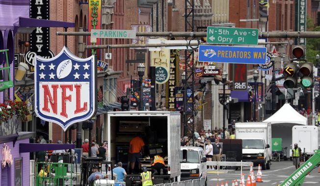A temporary NFL neon sign joins the permanent ones along Broadway as preparation continues for the NFL Draft Tuesday, April 23, 2019, in Nashville, Tenn. The NFL Draft is scheduled to be held Thursday through Saturday. (AP Photo/Mark Humphrey)