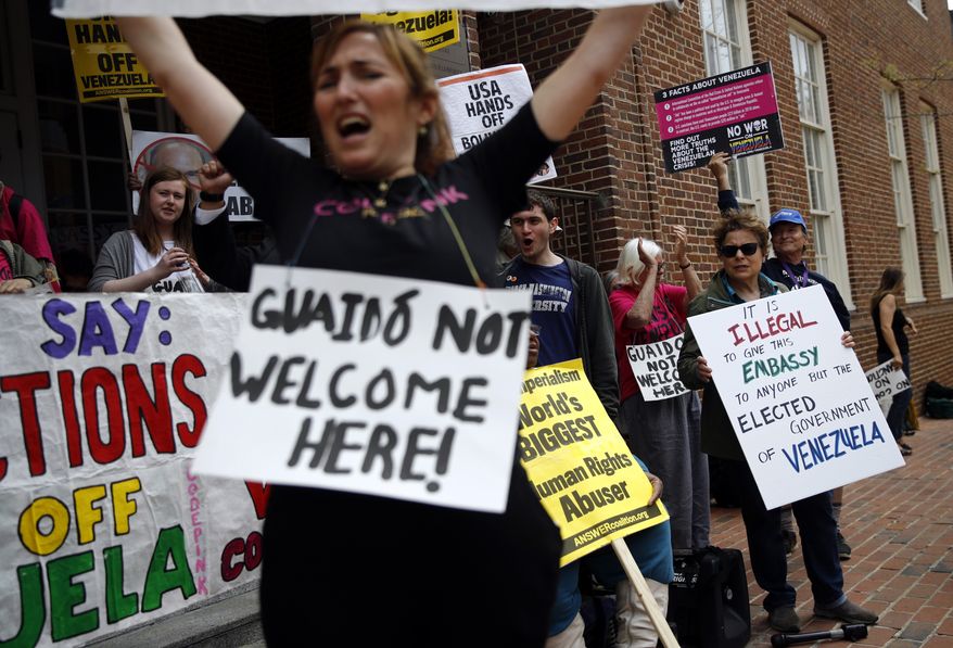 Protesters against Juan Guiado, opposition leader and self-proclaimed interim president of Venezuela, chant outside the Venezuelan Embassy, Thursday, April 25, 2019, in Washington. Activists are occupying the embassy to prevent representatives of Guiado from taking over the building. (AP Photo/Patrick Semansky)
