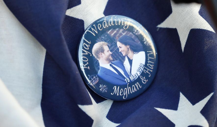 FILE- In this Thursday, May 17, 2018 file photo, a badge showing Prince Harry and Meghan Markle is pinned onto a US flag in Windsor, England. The child of Meghan Markle and Prince Harry will be seventh in the line of succession to the British throne, and also could be an American. The baby expected to arrive in the next few weeks would be the first citizen of Britain’s former colonies born into the upper echelons of the royal family. (AP Photo/Frank Augstein, File)