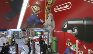 FILE - In this Nov. 15, 31, 2018, file photo, shoppers standing on an escalator passes by the logo of Nintendo at an electronics store in Tokyo. Japanese video game maker Nintendo Co. is reporting a 39 percent rise in profit for the fiscal year through March, 2019, on healthy software sales for its popular Switch console.(AP Photo/Koji Sasahara, File)