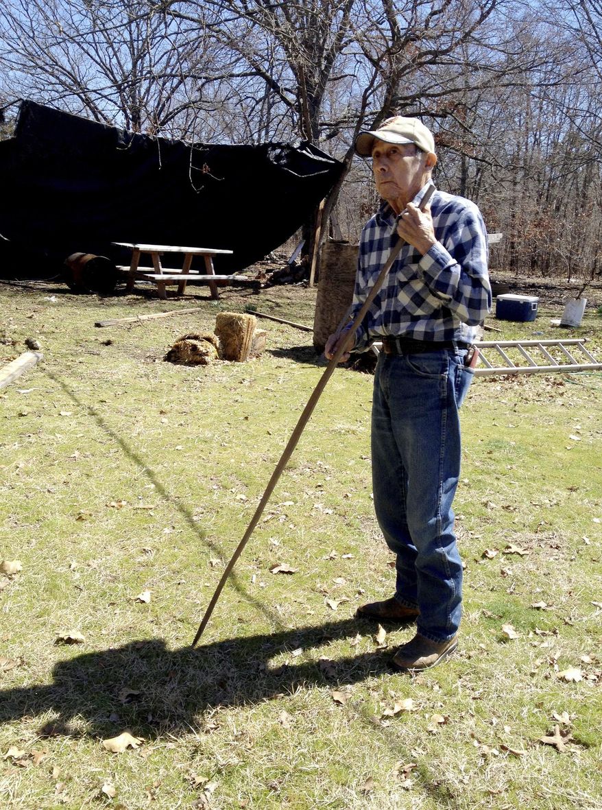 FILE - In this March 14, 2014, file photo, monolingual Cherokee speaker Mack Vann, 83, holds the start of a handmade bow in the backyard of his hime in Briggs, Okla. Vann, among the last members of the Cherokee Nation who spoke and understand the Cherokee language and only the Cherokee language, has died at the age of 88. Nephew Gary Vann says his uncle died Monday, April 22, 2019, in a Tahlequah, Oklahoma, hospital of pneumonia while undergoing treatment of an ongoing heart condition. (AP Photo/Kristi Eaton, File)