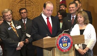 File - In this April 16, 2019, photo, Colorado Gov. Jared Polis, at podium, signs into law Senate Bill 19-181 at the State Capitol in Denver, Colo., The law overhauls state oil and gas rules, shifting the focus away from encouraging production and directing regulators to make public safety and the environment their top priority. Opponents of the new law said Thursday, April 25, 2019, they will not try to overturn it this year, as planned, but they may try in 2020 if they consider any of the new rules to be an overreach. (AP Photo/Dan Elliott/File)