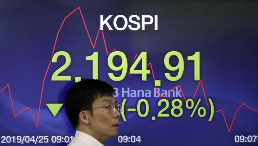 A currency trader walks by the screen showing the Korea Composite Stock Price Index (KOSPI) at the foreign exchange dealing room in Seoul, South Korea, Thursday, April 25, 2019. Asian shares were mixed Thursday after U.S. stocks closed lower, giving back some of its gains a day after the S&P 500 and Nasdaq hit record highs. (AP Photo/Lee Jin-man)