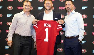 San Francisco 49ers first-round pick Nick Bosa, center, holds up a jersey next to general manager John Lynch, left, and coach Kyle Shanahan, right, during an NFL football news conference, Friday, April 26, 2019, in Santa Clara, Calif. (AP Photo/Tony Avelar )
