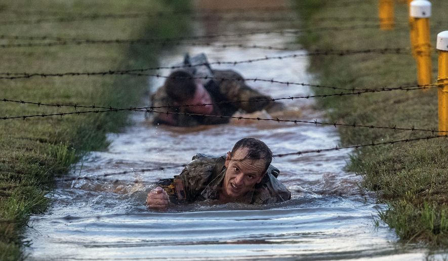 U.S. Army Capt. Michael Rose, of the 101th Airborne, crawls and under barbed wire strung across muddy water on the Melvesti course during the Best Ranger competition on Friday, April 12, 2019, at Fort Benning, Ga. Rose and his teammate Capt. John Bergman, background, won the event. Over 100 elite members of the U.S. military spent 60 grueling hours competing as two-member teams for the Best Ranger title. (AP Photo/John Bazemore)
