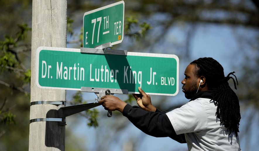 In this photo taken April, 20, 2019, public works employee Jerry Brooks changes a street sign from the The Paseo to Dr. Martin Luther King, Jr. Blvd. in Kansas City, Mo. More than 50 years after King was assassinated, the city's efforts to honor the civil rights leader has met opposition from citizens opposed to the renaming of The Paseo, one of the city's iconic boulevards. (AP Photo/Charlie Riedel)