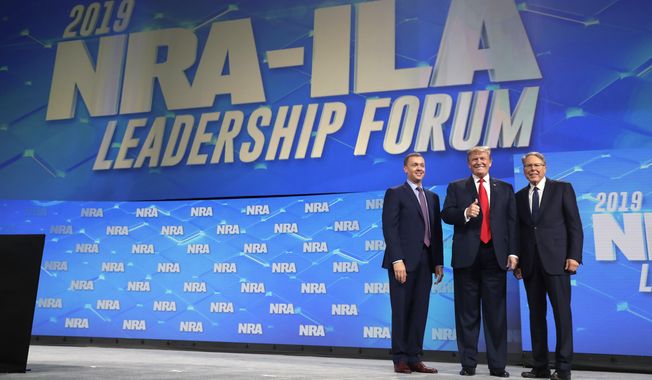President Donald Trump stands with Chris Cox, Executive Director of the National Rifle Association’s Institute for Legislative Action, left, and NRA executive vice president and CEO Wayne LaPierre, right, as he arrives to speak to the annual meeting of the National Rifle Association, Friday, April 26, 2019, in Indianapolis. (AP Photo/Evan Vucci) **FILE**