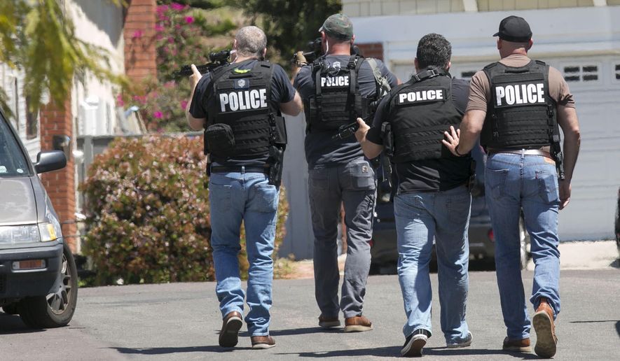 Heavily armed San Diego police officers approach a house thought to be the home of 19 year-old John T. Earnest, who is a suspect in the shooting of several people in a Poway synagogue, on Saturday, April 27, 2019, in San Diego, Calif. A gunman used an AR-type assault weapon to shoot worshippers at Chabad of Poway, San Diego County Sheriff William Gore said. (John Gibbins/The San Diego Union-Tribune via AP)