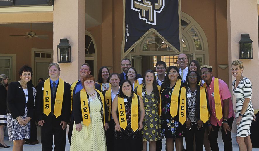 In this Monday, April 22, 2019 photo, The first graduating class from the Inclusive Education Services (IES) program at the University of Central Florida pose for a photo with administrators and Thad Seymour Jr., UCF Acting President, at Burnett House in Orlando, Fla. (Ricardo Ramirez Buxeda/Orlando Sentinel via AP)