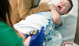 In this April 18, 2019, photo Broderick Hansen is held by his mother Jennifer Hansen as Kristen Sklenar delivers a measles vaccine in Omaha, Neb. (Kent Sievers/Omaha World-Herald via AP) **FILE**