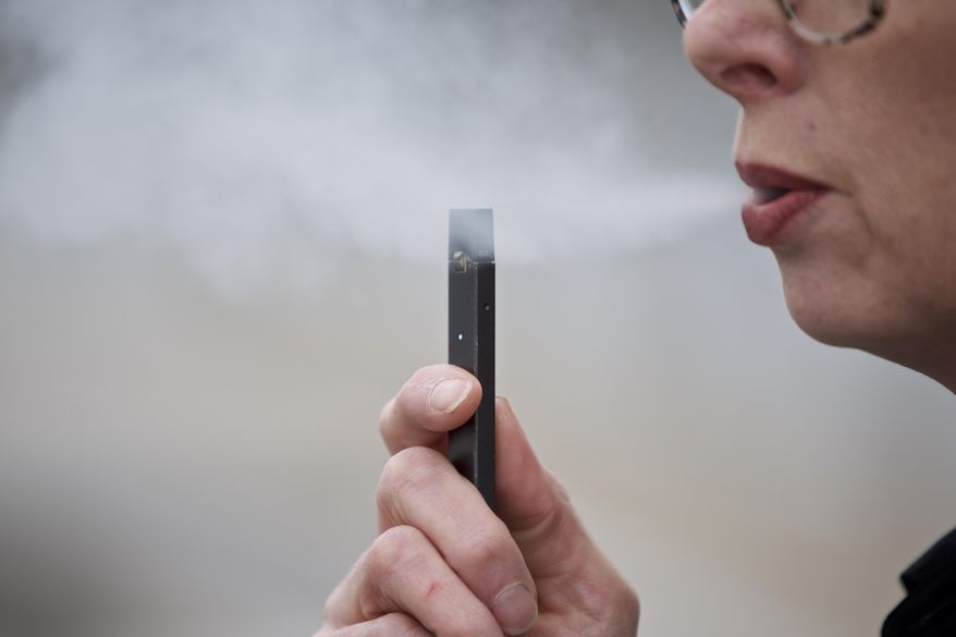 A woman exhales a puff of vapor from a Juul pen in Vancouver, Wash., Tuesday, April 16, 2019. On May 16, 2019, the Connecticut House of Representatives moved the state a step closer to boosting the legal age to purchase tobacco and vaping products from 18 to 21. (AP Photo/Craig Mitchelldyer)