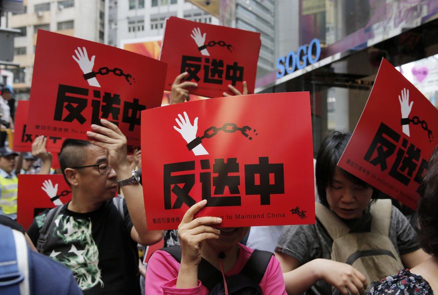 People raise placards reading " Against Extradition law" as thousands of protesters march along a downtown street against the extradition law in Hong Kong Sunday, April 28, 2019. Thousands of people protest to express their concerns about a proposed new extradition law that would make it possible for people to be sent to mainland China to face the justice system there. (AP Photo/Vincent Yu)
