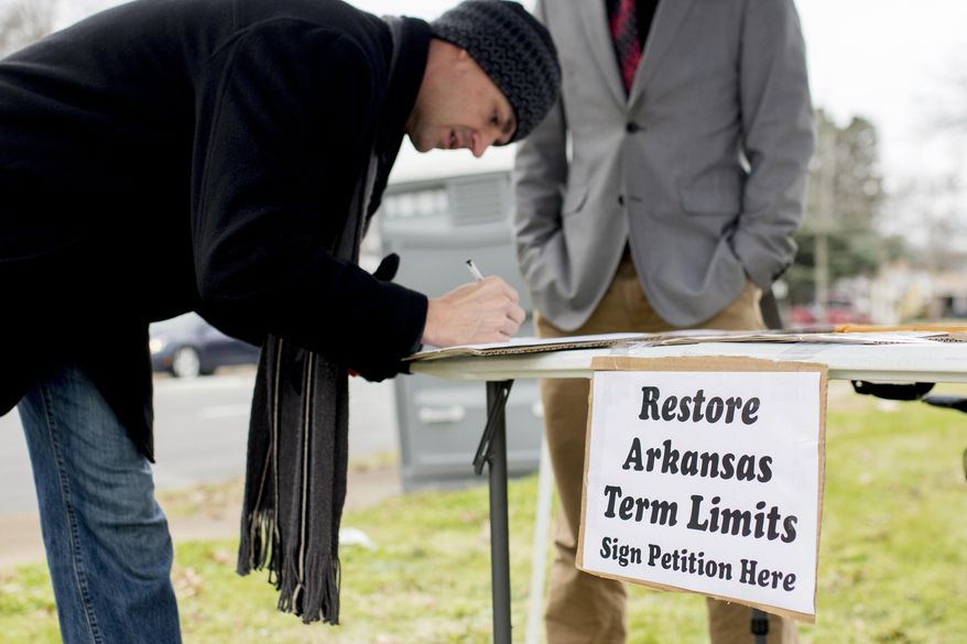 FILE - In this Jan. 18, 2016 file photo, Stuart Rubio, left, signs a petition to limit lawmakers terms in Little Rock, Ark. Arkansas was one of the first states to cap how long someone can serve in the Legislature nearly three decades ago, but competing term limit measures on the ballot next year could test just how far voters are willing to go in limiting lawmakers' time in office. In the legislative session that just wrapped up, Arkansas lawmakers sent voters a proposal that would rework the term limits on House and Senate members for the second time in the past several years.(AP Photo/Gareth Patterson, File)