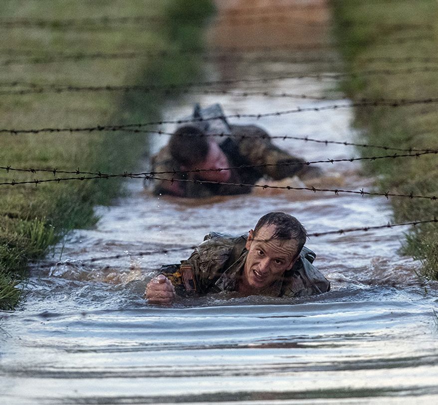 U.S. Army Capt. Michael Rose, of the 101th Airborne, crawls and under barbed wire strung across muddy water on the Melvesti course during the Best Ranger competition on Friday, April 12, 2019, at Fort Benning, Ga. Rose and his teammate Capt. John Bergman, background, won the event. Over 100 elite members of the U.S. military spent 60 grueling hours competing as two-member teams for the Best Ranger title. (AP Photo/John Bazemore)